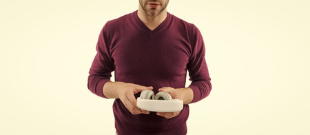 Young millennial man hold audio headphones for listening music isolated on white, cropped view