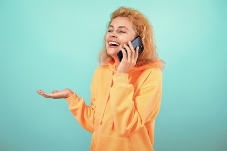 Communication. Woman speak on smartphone isolated on blue. Millennial woman has phone conversation....