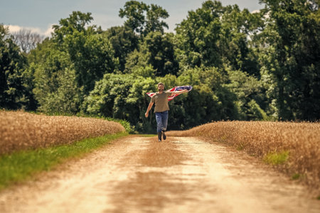 Flag of USA. Independence day. Man in field. Man with American flag in crop field. Independence day of America. 4th of July. American labor day. American flag and man farmer. Country lifeの写真素材