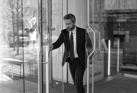 Adult entrepreneur at office door. Hispanic businessman in suit leaving office building. Boss...