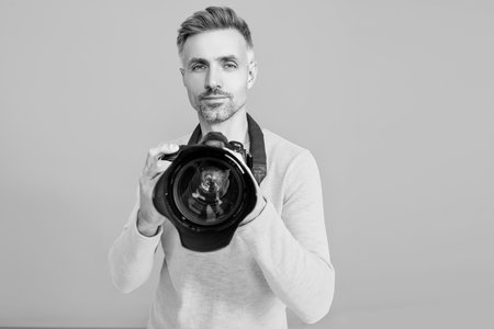 Man photographer isolated on blue. Photographer hold photo camera. Professional photography. Shooting session. Photoshoot. Man taking photo picture. Photographing with camera. Selective focusの写真素材