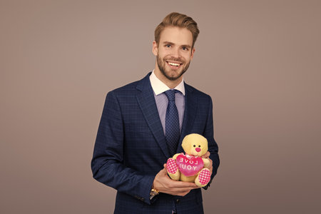 Business man with corporate gift isolated on grey. Corporate present. Successful boss hold gift toy. Valentines day. Businessman prepare for romance date. Secret valentine at business corporateの写真素材