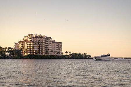 Summer vacation. Fisher island residential building and luxury yacht boat. Motorboat passing Fisher island, Miami. Miami architecture, Florida. Luxury yacht boat at Fisher island. Waterfront viewの写真素材