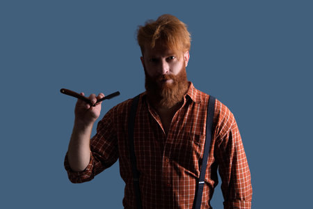 Hairdresser at barbershop isolated on grey. Hairdresser man. Professional barber man hold retro razor. Handsome hairstylist with haircut. Barbershop. Man hairdressing and barbering. Retro bladeの写真素材