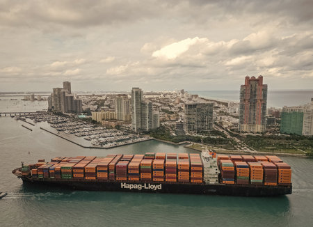 Miami, Florida, USA - January 16, 2025: Container ship. Cargo ship with container in Miami, Hapag Lloyd. Freight container loaded on cargo vessel in Miami. Aerial view cargo ship entering harborのeditorial素材