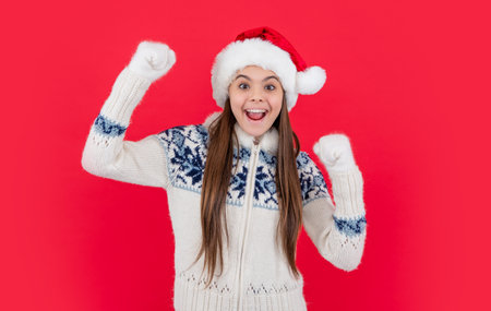 christmas holiday. amazed teen girl in red christmas santa hat in studio. teen santaの写真素材