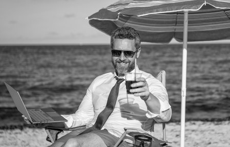 Traveling for client meetings. Man freelance worker online at sea beach. Businessman on summer. Online freelance work. Businessman office worker with laptop. Business man using laptop in beachの写真素材