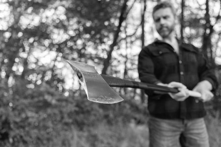 Lumberjack with axe in selective focus. Lumberjack in forest. Man with axe blade. Axe in man hand chopping wood. Cutting wood. Sharp bladeの写真素材