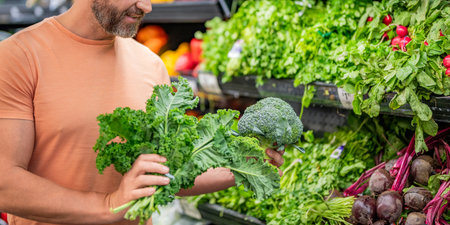 Grocery consumer. Broccoli and kale cabbage. Man shopping vegetable in grocery store. Healthy lifestyle. Fresh food store. Man in grocery store. Man shopping in vegetable supermarket. Green vitaminの写真素材