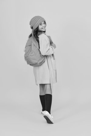 Knowledge day. Knowledge and education. School education. Student in autumn style. Young girl look back isolated on yellow. September 1. Study in college. Student girl having backpack. Back to schoolの写真素材