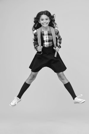 School education. Happy student. Young girl jumping isolated on yellow. Study in college. Student girl jumping with backpack. Back to school. Knowledge day. Knowledge and educationの写真素材