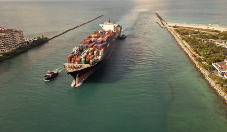 Export and import. Cargo business. Port of Miami. Cargo ship with container, aerial. Freight container on cargo vessel. Cargo ship vessel leaving port. Container ship. Global supply chain backboneの写真素材