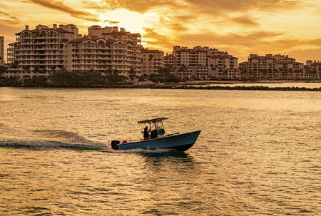 Miami canal with boat. Fisher island residential building and luxury yacht boat. View on Fisher island, Miami. Motor boat yacht floating to marina. Luxury yacht boat at Fisher island. Summer vacationの写真素材