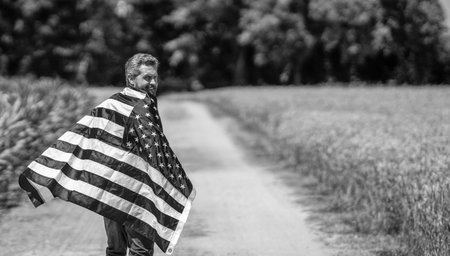 4th of July. American labor day. American flag and man farmer. Flag of USA. Independence day. Man in field. Man with American flag in crop field. Independence day of America. Copy space bannerの写真素材