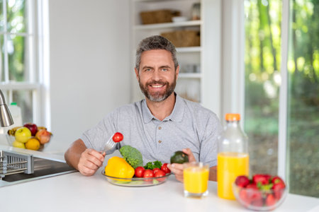 Enjoying healthy food. Man eat morning breakfast in kitchen. Mature man eating lunch. Morning at home. Breakfast in kitchen. Man eating organic vegetable and juice for lunch. Colorful lunchの写真素材