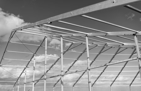 Framework construction architecture. Architectural detail. Installation of metal structure at cloudy sky. Metal construction. Structural design engineering. Structure engineering at building siteの写真素材