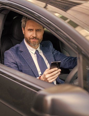 Car dealer. Dealership. Man in suit using phone in car. Hispanic businessman dealer with phone....