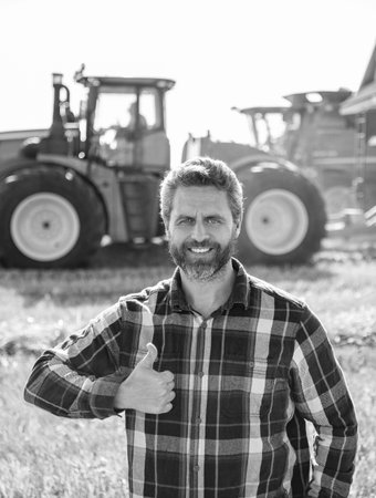 Agronomist man harvesting at crop field. Ripe agriculture. Harvest man at field. Farmer agronomist. Crop harvest. Farmer check wheat. Agricultural wheat at harvest time. Countryside crop. Thumb upの写真素材