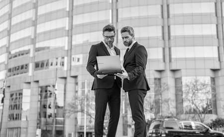 Business men freelancing outdoor. Business online. Men working on laptop. Businessmen working online. Businessmen in suit with laptop. Online working. Businessmen checking email. Successful businessの写真素材