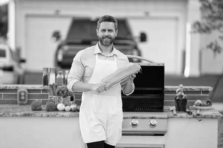 Hispanic man preparing tuna fish in barbecue. Chef barbecuing seafood. Backyard BBQ. Man cook fish....
