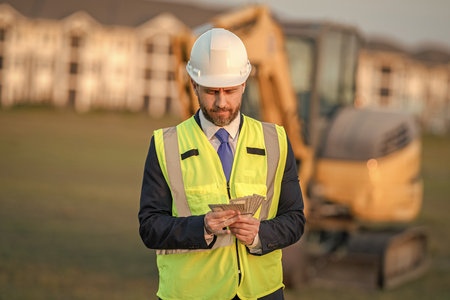 Businessman counting money at site. Businessman investing money in construction business. Successful...