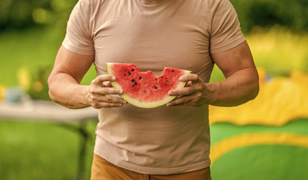 Man with watermelon. Picnic guy with watermelon outdoor in summer camp. Man eating watermelon. Mature man eat fruit. Man enjoying juicy fruit vitamin. Camping. Forest camp restの写真素材