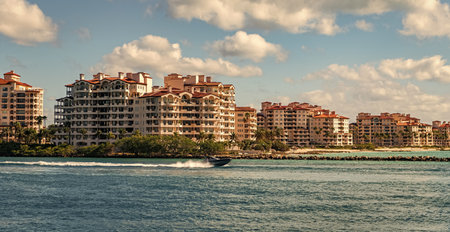 Yacht go to marina. Boating and yachting. Luxury lifestyle. Yacht at Fisher island luxury residential building. Vacation on summer. Fisher island building. Luxury motor boat yacht. Touristic spotの写真素材