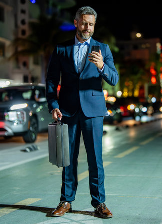 Successful businessman chatting online. Businessman walking night city. Business man chat on phone...