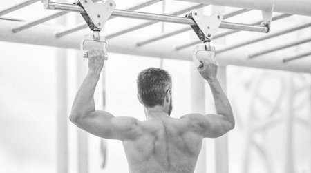 Man sportsman do pulling exercise. Man muscular back athlete doing pull up in outdoor gym. Sport...