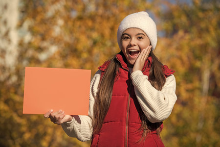 teen girl presenting fall season discount. seasonal sale. autumn girl hold blank paper for copy...