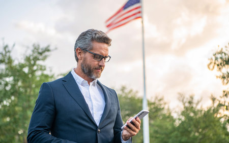 American business man with phone. Business fast communication. Messaging and texting. Business man chatting on phone outdoor. Businessman using phone. Man phone chat, copy spaceの写真素材
