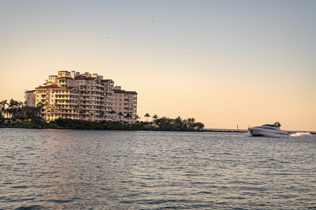 Miami architecture and motorboat, Florida. Luxury yacht boat at Fisher island. Summer vacation. Fisher island residential building and luxury yacht boat. Motorboat passing Fisher island, Miamiの写真素材