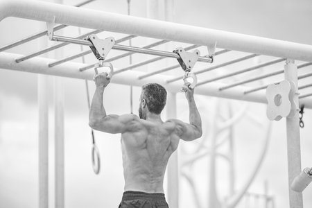 Man muscular back athlete doing pull up in outdoor gym. Sport lifestyle. Muscular biceps and...