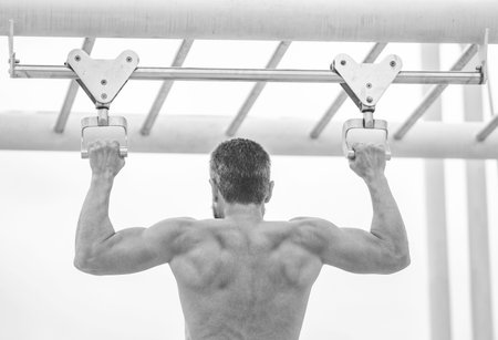 Sport training. Man sportsman do pulling exercise. Man muscular back athlete doing pull up in...