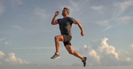 Runner man running. Fitness and sport. Man running against blue sky. Sport lifestyle. Sportsman...