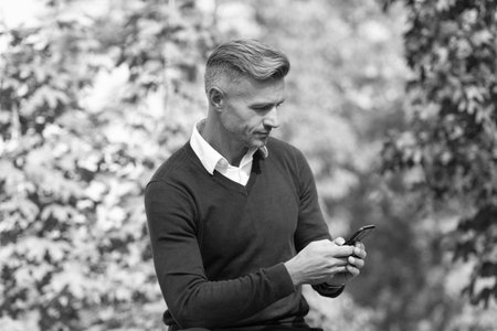 Businessman use phone outdoor. Sitting mature business man. Autumn style. Businessman in autumn...