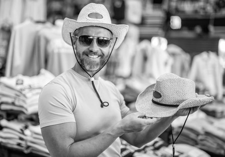 Male accessories store. Trendy fashion store. Handsome man trying on hat. Hat male fashion shop. Man shopping fashion hat. Stylish man in boutique. Mature man choosing hat. Cowboy styleの写真素材