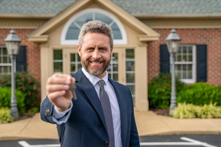 Broker man. House insurance. Realtor offering new home. Realtor in suit hold key outdoor. Real estate agent showing house for sale. Property insurance. Real estate market. Selective focus