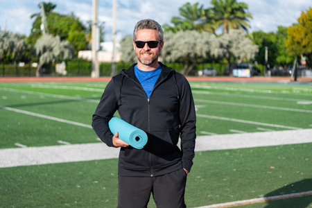 Healthy lifestyle. Fitness and sport. Yoga mat for training. Hispanic sportsman. Man in sportswear with fitness mat in stadium. Fit your body. Yoga coach. Sport man ready for workout
