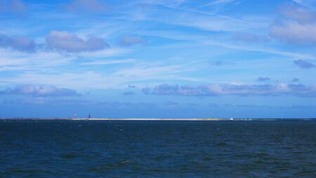 Panorama von Wangeroge vom Meer aus mit Horizontlinie und Wolken am Himmelの写真素材