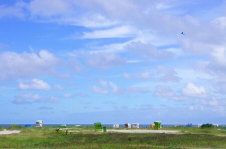 Panorama on the North Sea of Dunes with beach chairs and clouds in the blue skyの写真素材