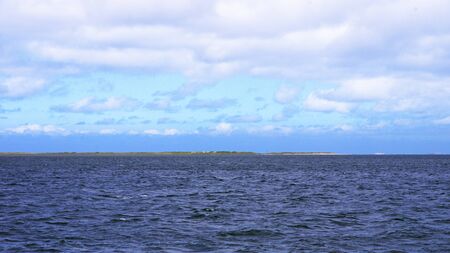 Horizont auf See mit Meer und Wolken am Himmel und Land in der Weiteの写真素材