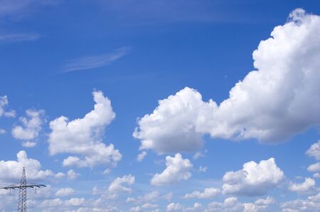 Panorama of fluffy sheep clouds against a blue sky with power lineの写真素材