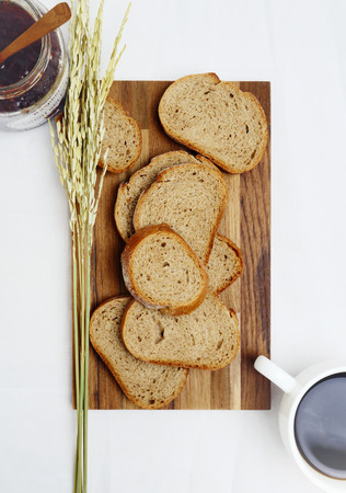 Bread sliced on a chopping board with strawberry jam and coffee. Still life.