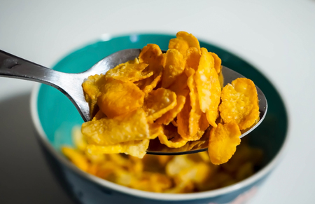 Spoon dipped cereal from green bowl before filling milk in it.