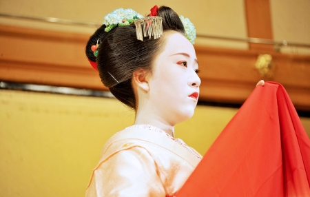 dancing girl in a traditional yellow kimono holding a red shawlのeditorial素材