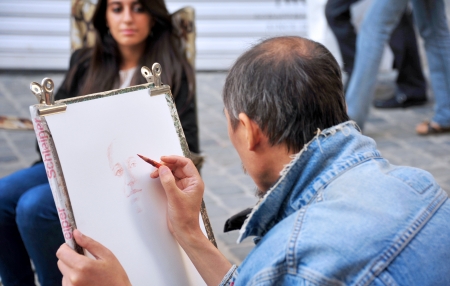 an artist wearing jeans jacket drawing the picture of the girl sitting in front of himのeditorial素材
