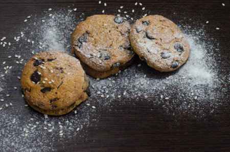 Cookies with chocolate on dark background with sugar powder and seasameの写真素材
