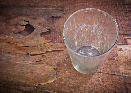 dirty old glass with spider web inside on wooden backgroundの写真素材