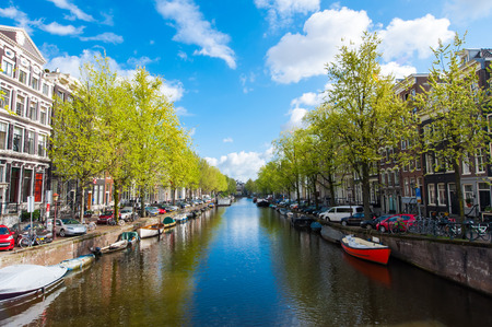 Amsterdam canal with boats along the bank during the sunny day, Netherlands.のeditorial素材
